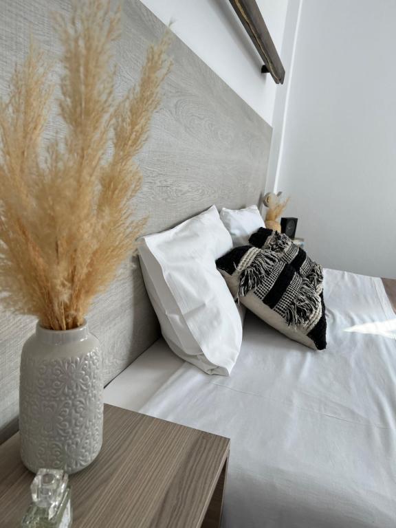 a bed with two pillows and a vase on a table at Fatolitis Studios in Masouri