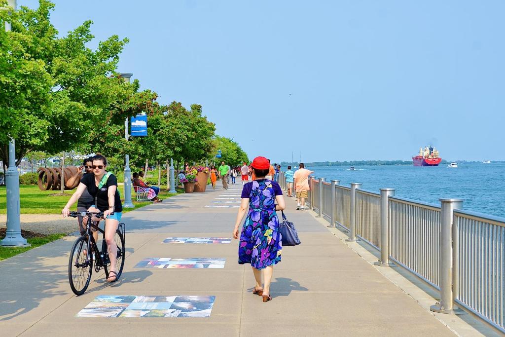 duas pessoas a andar e a andar de bicicleta num passeio junto à água em Detroit Riverwalk Loft em Detroit