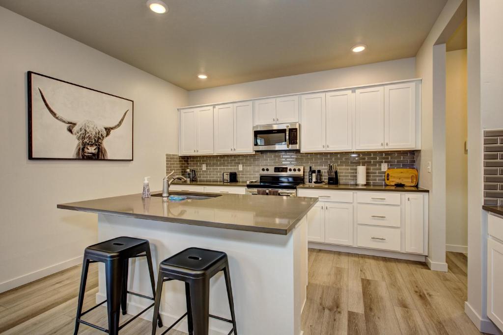una cucina con armadi bianchi e un bancone con sgabelli di Hygee House Brand New Construction near Ford Idaho Center and I-84! Plush and lavish furniture, warm tones to off-set the new stainless appliances, play PingPong in the garage or basketball at the neighborhood park a Meridian