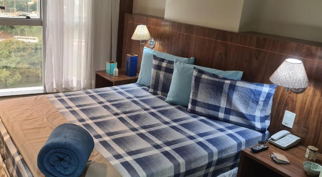 a bedroom with a bed with a blue plaid at Lindíssimo Flat em Taguatinga. Conforto, tranquilidade e paz em um ambiente perfeito. in Brasilia