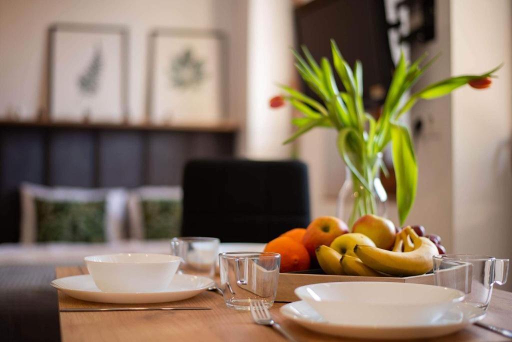 a table with a bowl of fruit and a vase of flowers at Place4You in Ostróda