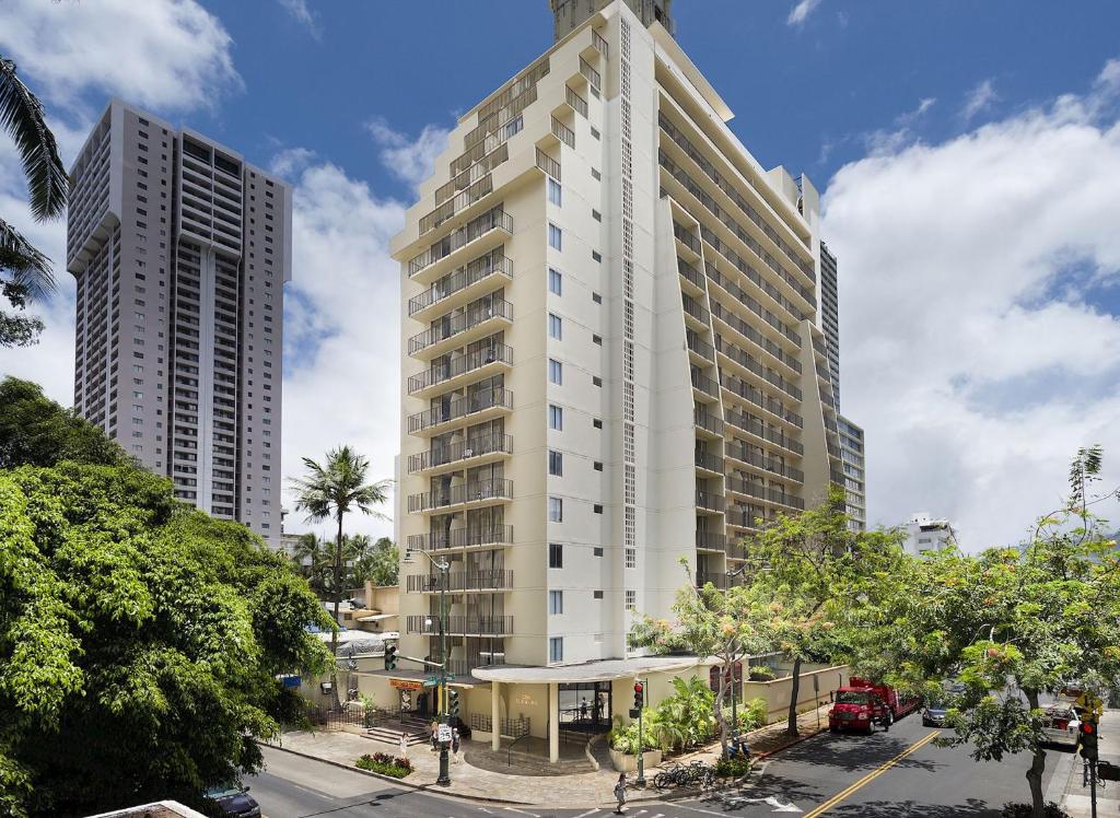 Ohia Waikiki Studio Suites في هونولولو: مبنى أبيض طويل مع مبنيين طويلين