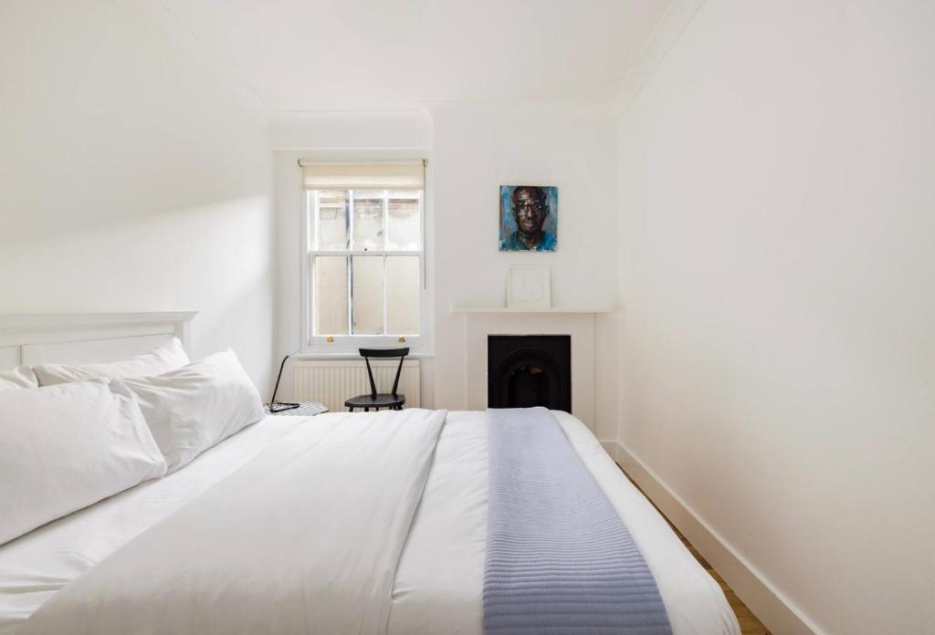 a large white bed in a white room with a fireplace at Cool, Quiet Notting Hill 2 BED APT in London