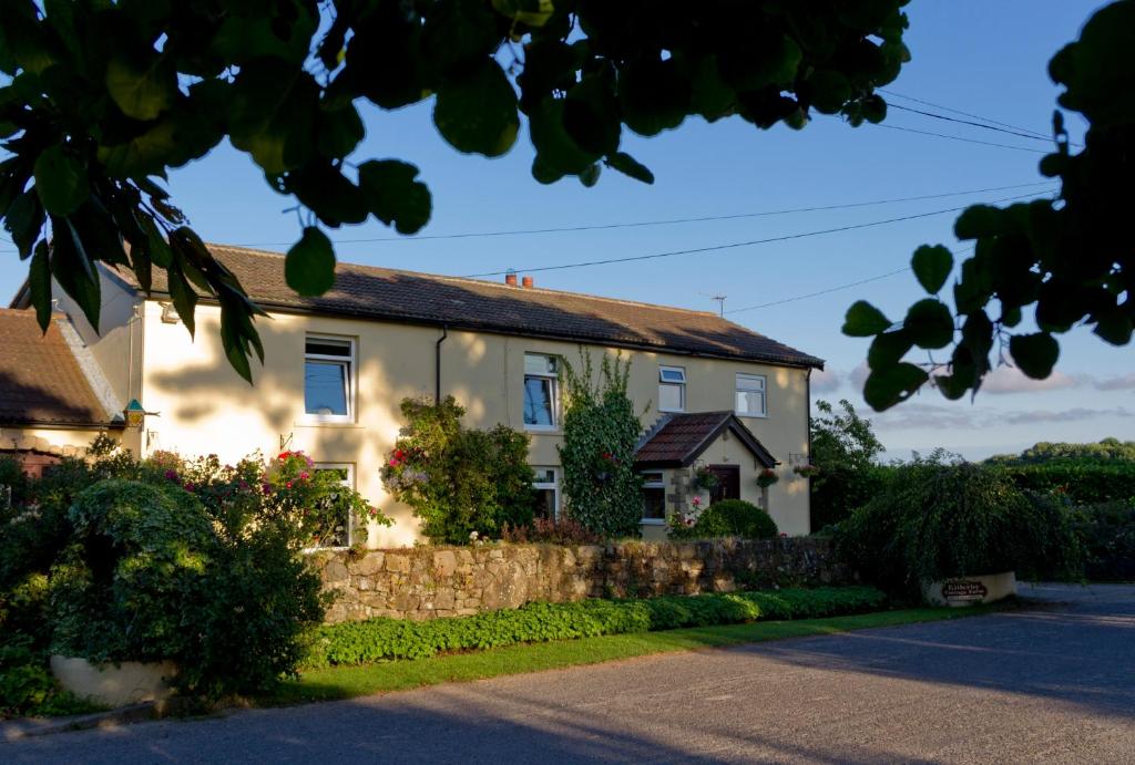 une maison blanche avec une clôture en pierre devant elle dans l'établissement Killerby Cottage Farm, à Scarborough