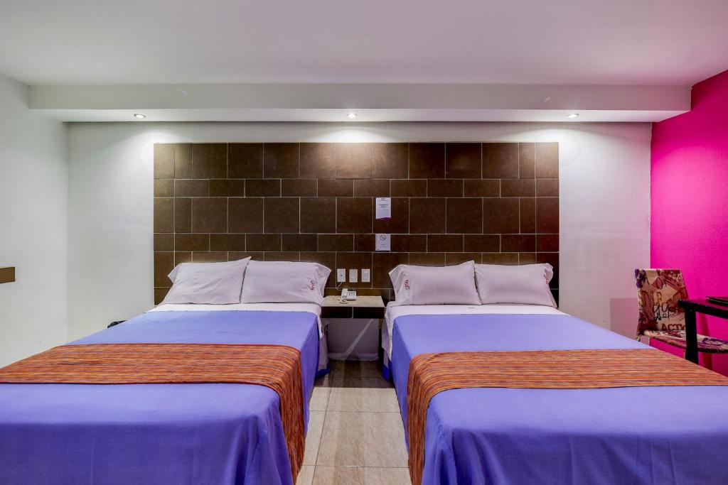 two beds in a room with pink and purple at First Inn Hotel & Business in Texcoco de Mora