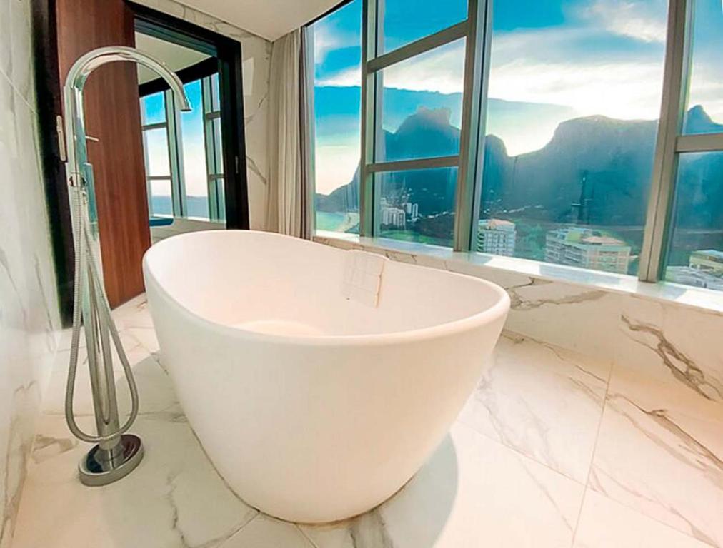 a white bath tub in a bathroom with a window at Hotel Nacional Vista Mar c/ Banheira in Rio de Janeiro