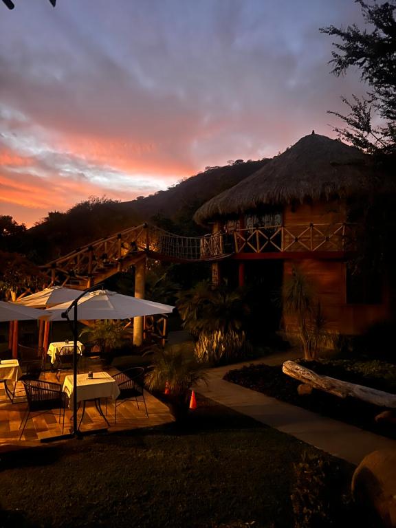 a building with a grass roof with tables and umbrellas at Villa Armonia Hotel & Spa in Jocotepec