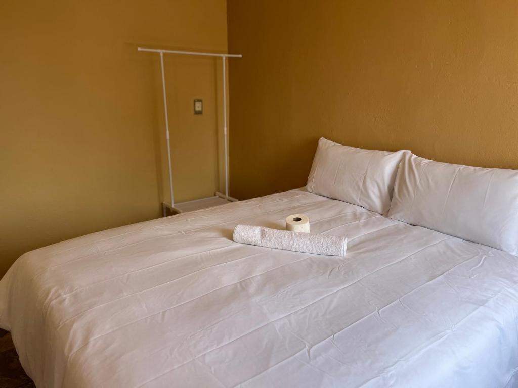 a white bed with a rolled up towel on it at Eldos Guest House in Soweto