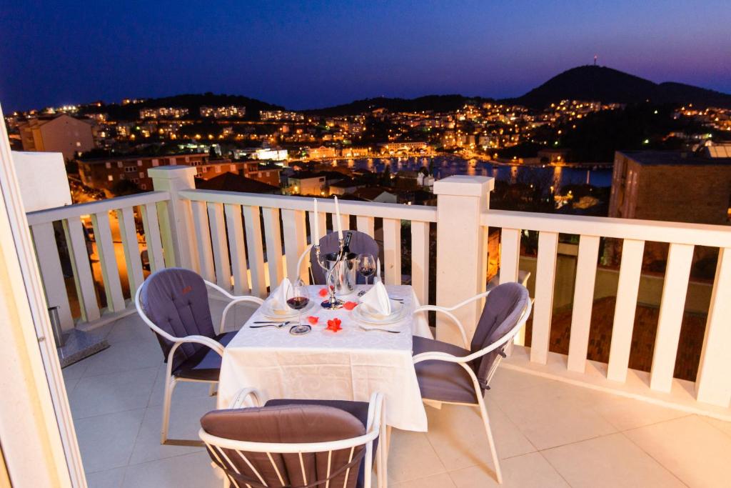 - une table blanche avec des chaises sur un balcon la nuit dans l'établissement Apartment Denis, à Dubrovnik