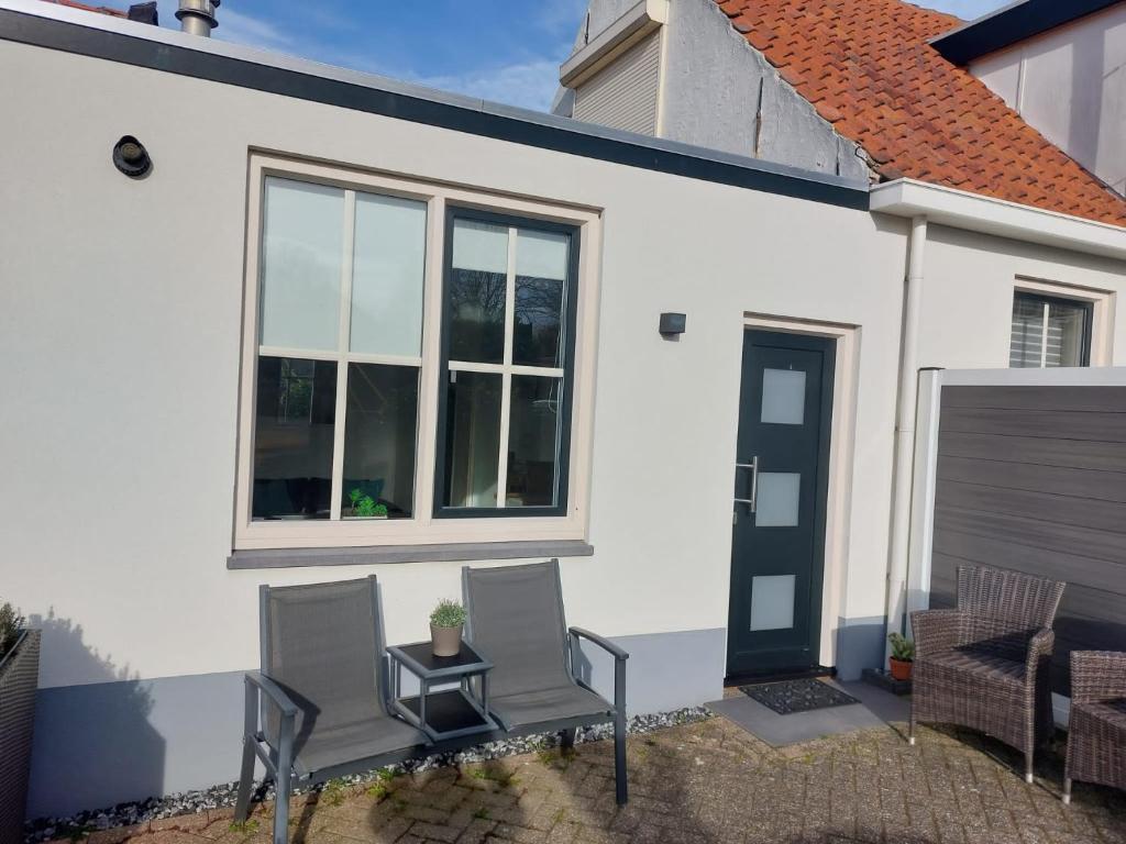 uma casa branca com duas cadeiras e uma mesa em vakantiehuisje Cottage em Aagtekerke