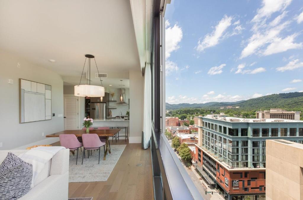 a living room and kitchen with a view of a building at 'Panoramic Pack Square' A Luxury Downtown Condo with views of Pack Square Park at Arras Vacation Rentals in Asheville