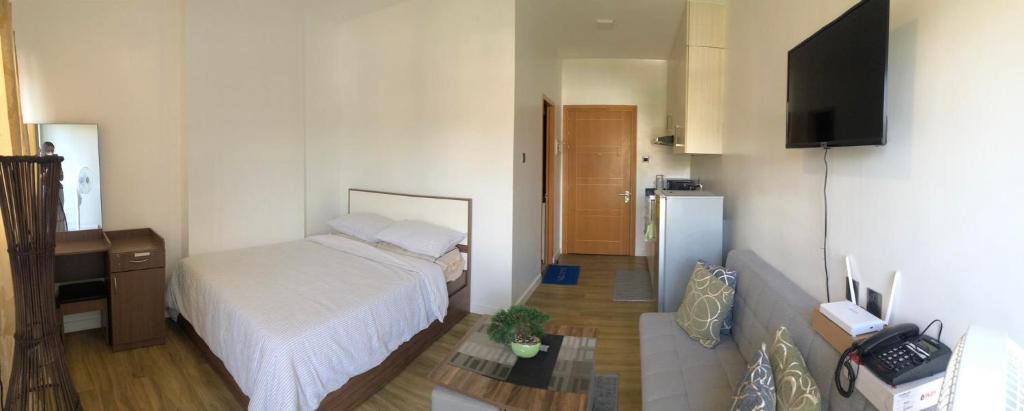 Dormitorio pequeño con cama y nevera en Antara Residential Condominium, en Talisay