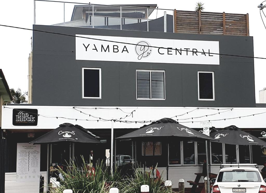 a restaurant with umbrellas in front of a building at Yamba Central in Yamba