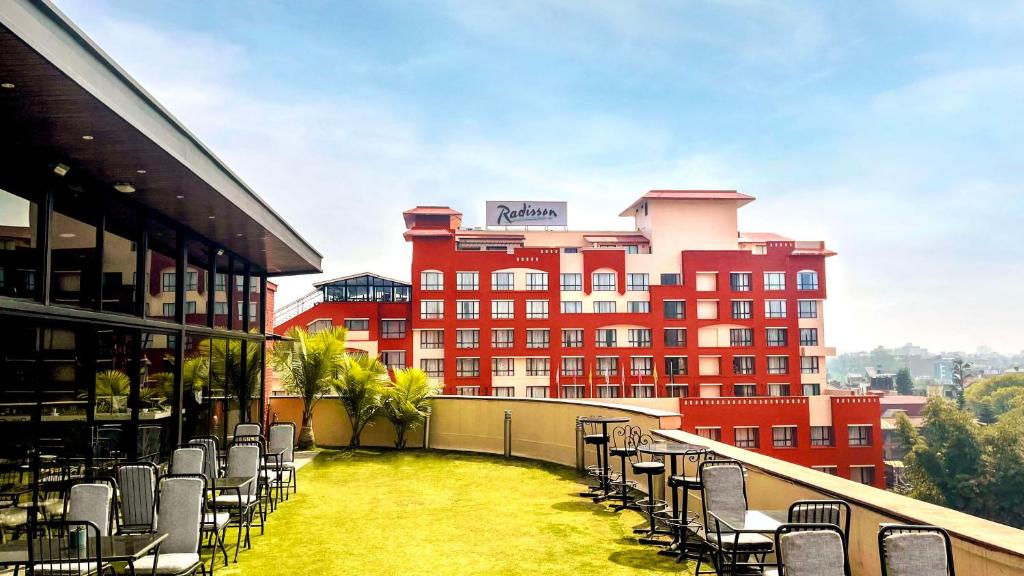 加德滿都的住宿－加德滿都麗筠酒店，一个带椅子的阳台和一座红色的大建筑