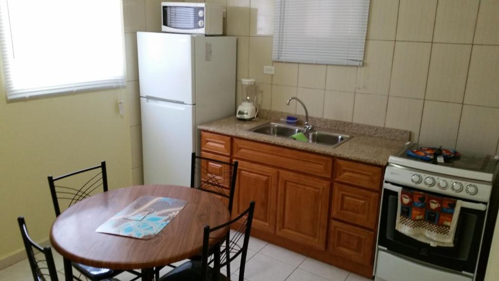 a kitchen with a table and a white refrigerator at Paramira Apartment in Oranjestad