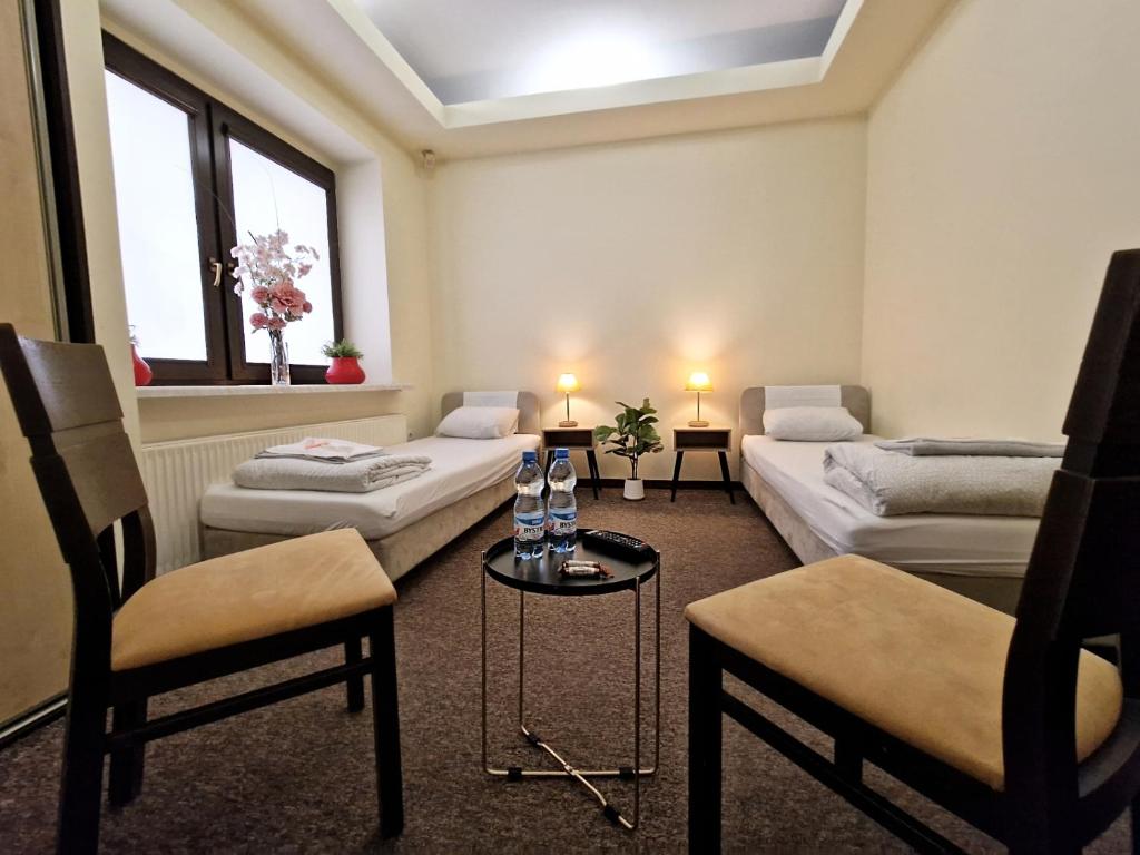 ワルシャワにあるHelvetia Plus B&Bのリビングルーム(ベッド2台、テーブル、椅子付)