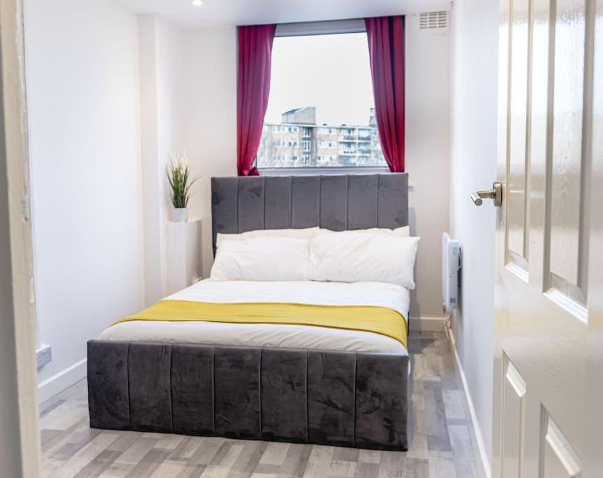 Cama en habitación pequeña con ventana en Pristine Relocation Apartments en Londres