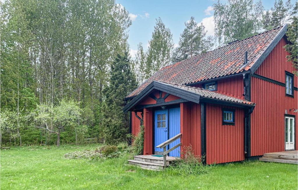 una casa roja con una puerta azul en un campo en Amazing Home In Grisslehamn With Sauna en Grisslehamn