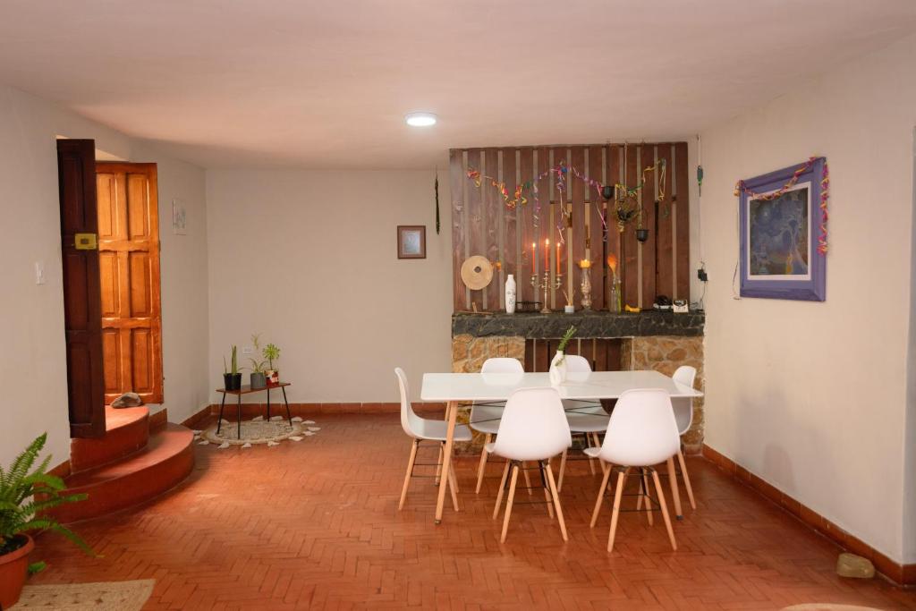 a dining room with a table and white chairs at Kinti Wasi Casa de Campo in Los Baños del Inca
