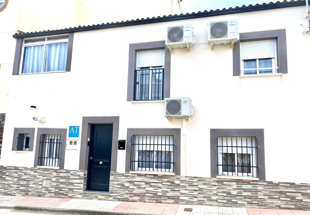 een wit huis met een blauwe deur en ramen bij CASA GODOY in Cáceres