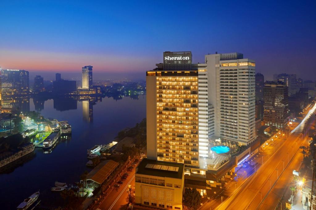 فندق وكازينو شيراتون القاهرة في القاهرة: مبنى طويل مع إضاءة في مدينة في الليل