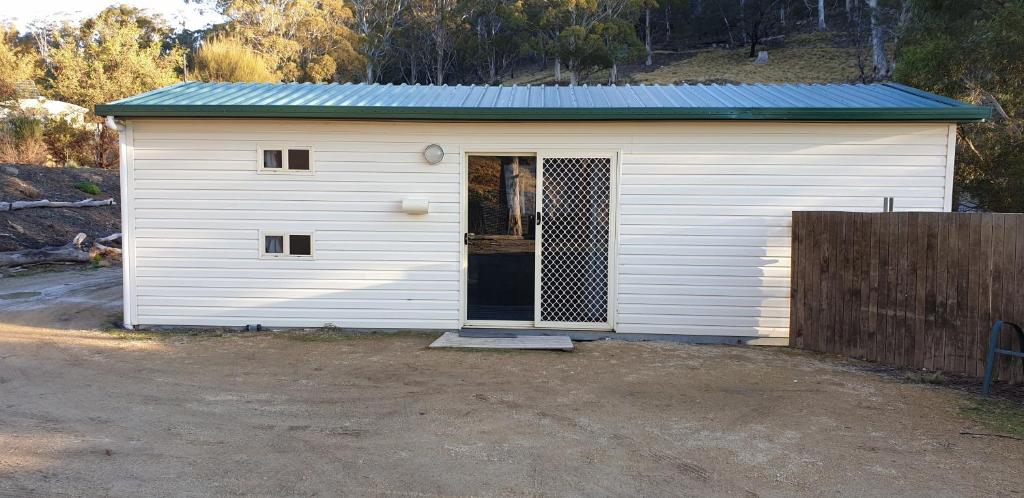 eine weiße Garage mit einer Tür und einem Zaun in der Unterkunft Mount Rumney Escapes - 1h Haven Horse House in Mount Rumney