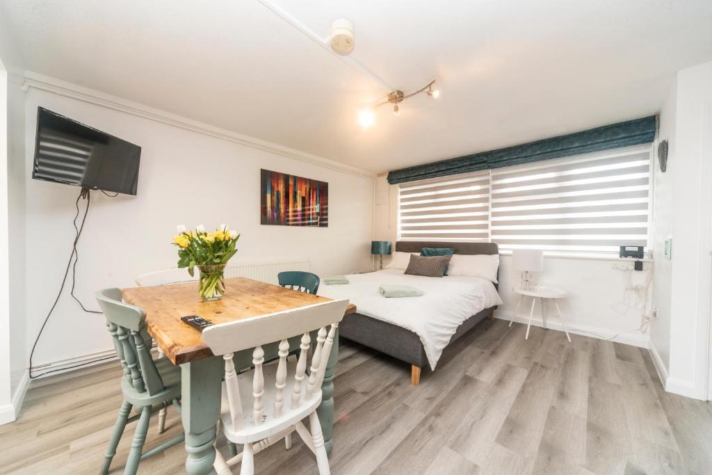 a living room with a bed and a table and a room with a bed at 10 Boutique Studio Apartment near Tube - quiet location in Little Missenden