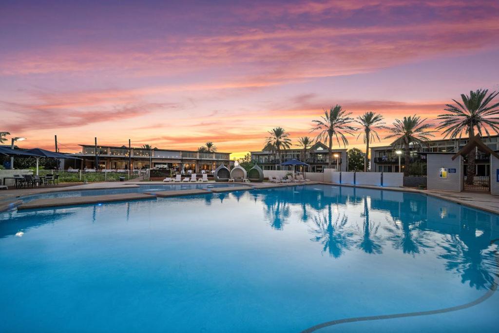 a large swimming pool with a sunset in the background at Mantarays Ningaloo Beach Resort in Exmouth