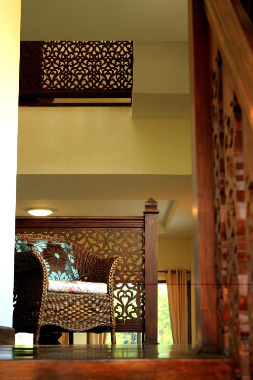 A carved-wood interior landing overlooks a wicker chair and a sunlit lower level.