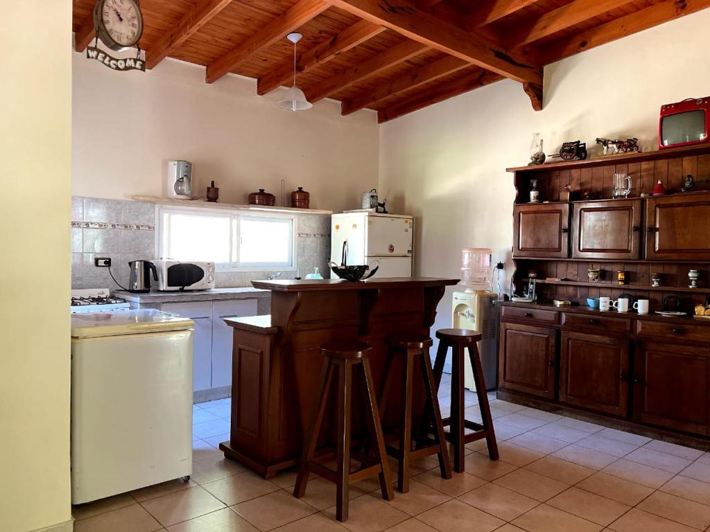una cocina con armarios de madera y una barra con taburetes en Finca Lo de Jose en La Banda