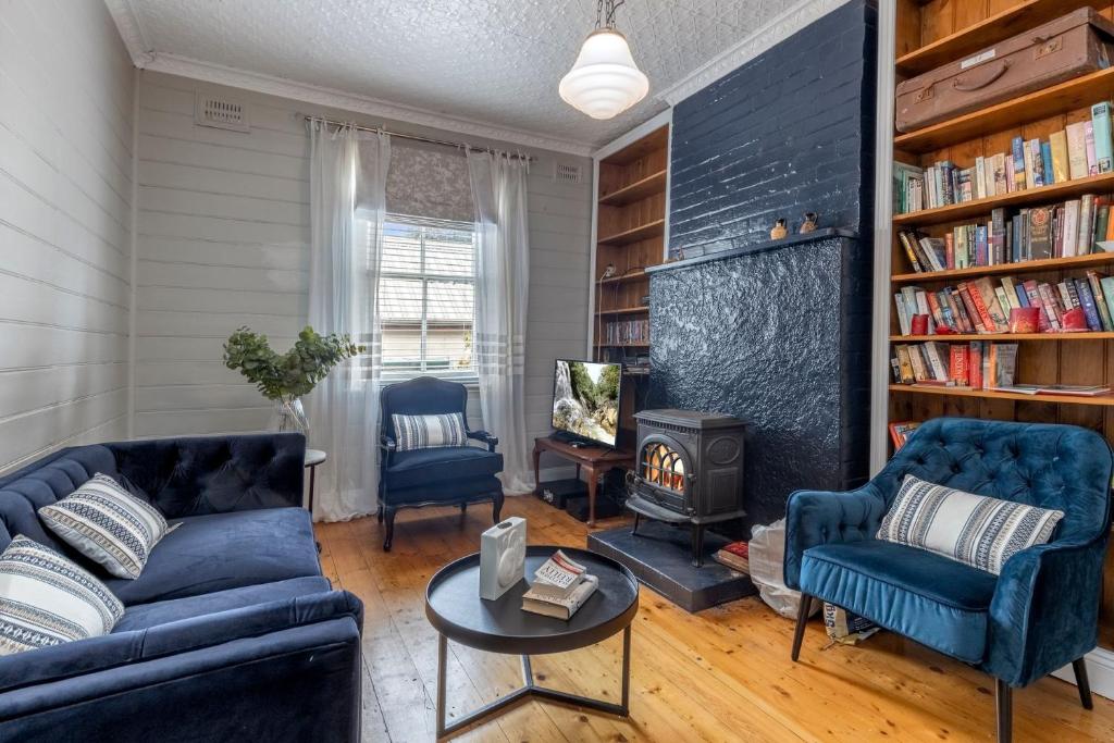 a living room with two blue couches and a fire place at Bluebell Cottage in Katoomba