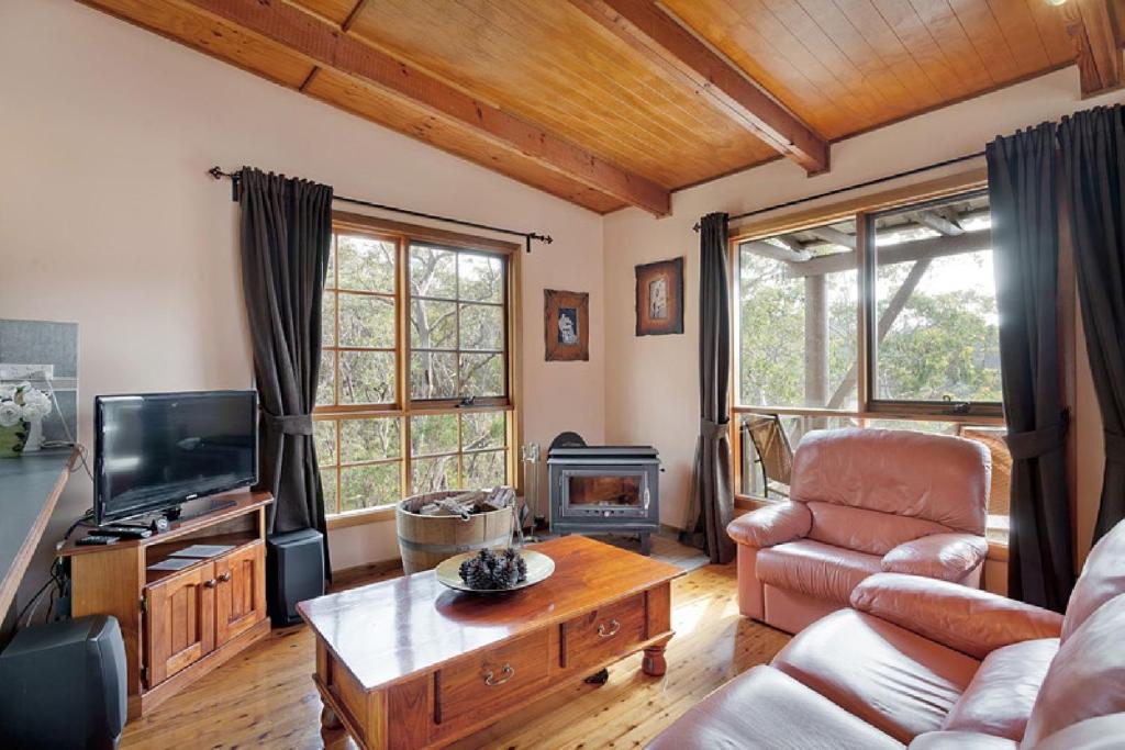 a living room with a couch and a tv at Observatory Cottage in Leura