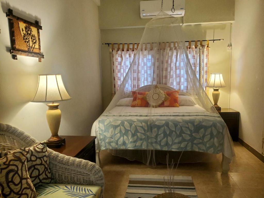 a bedroom with a bed and a chair and two lamps at Sunbreeze Ocho Rios - A spacious, homely apartment in Ocho Rios