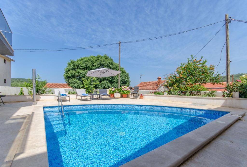 a swimming pool with an umbrella in a house at Apartments Villa LA in Veliki Drvenik