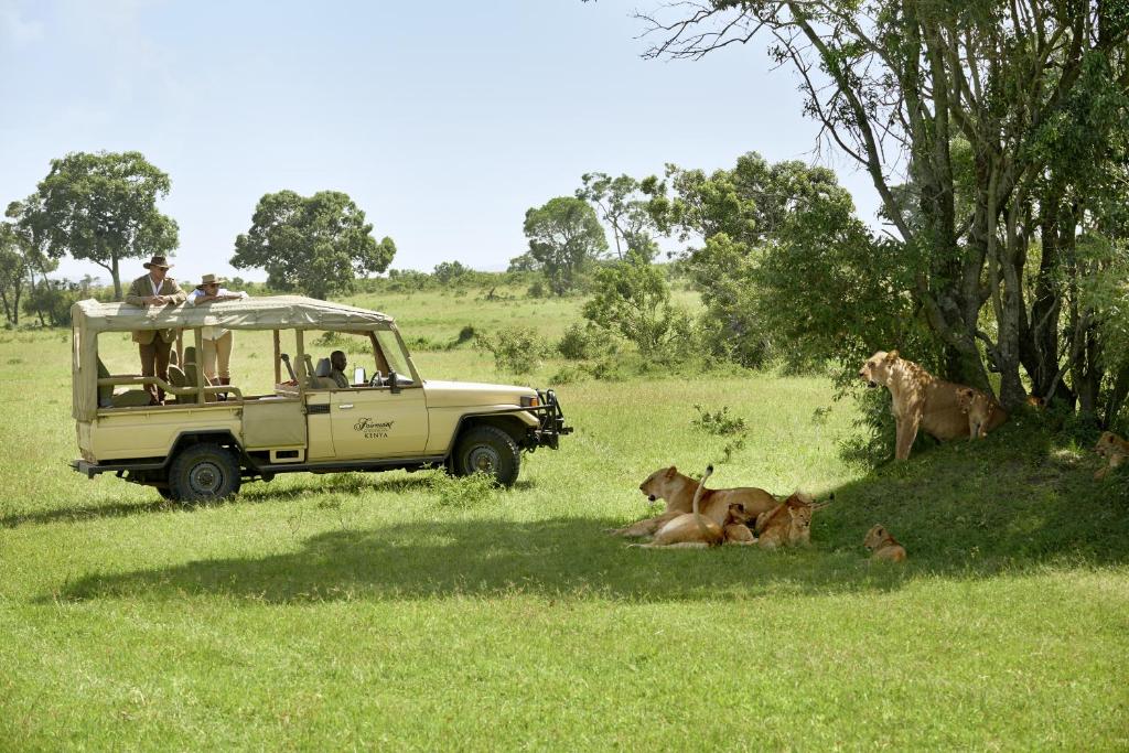 eine Gruppe von Personen in einem Fahrzeug auf einem Feld mit Tieren in der Unterkunft Fairmont Mara Safari Club in Aitong