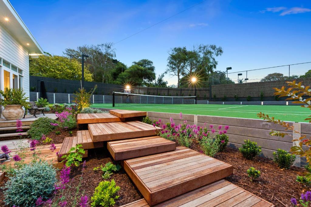 a garden with wooden benches and a tennis court at Sun Valley - Boutique Portsea Accommodation in Portsea