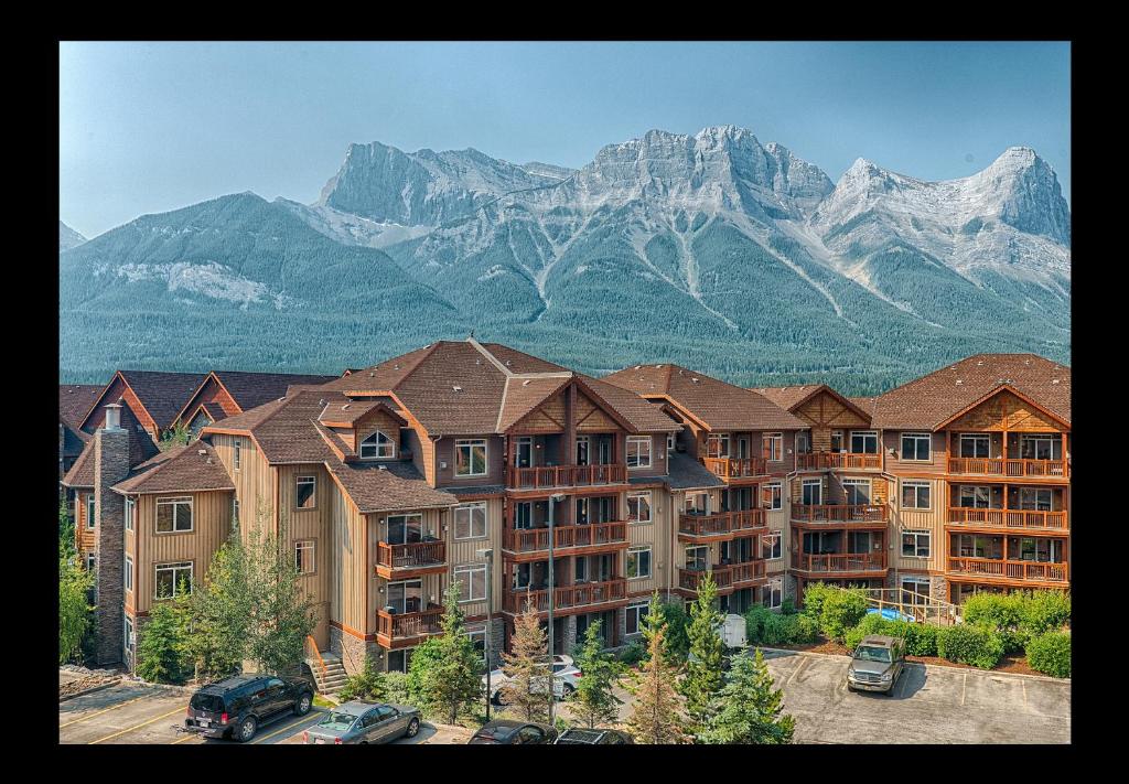 a large apartment building with mountains in the background at Falcon Crest Lodge by CLIQUE in Canmore