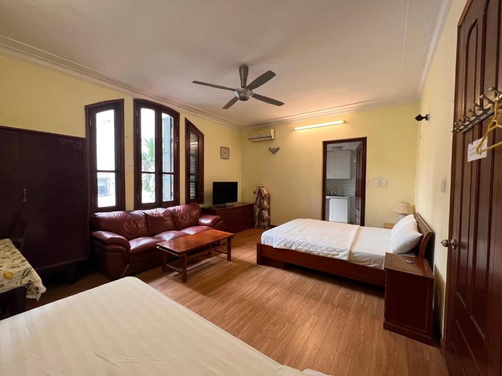 a bedroom with a bed and a couch and a ceiling fan at French-styled house in Hanoi