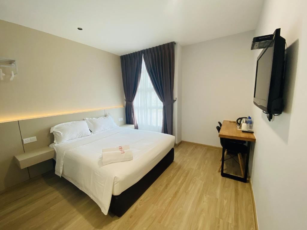 um quarto de hotel com uma cama e uma televisão em Hotel U and Me em Kulai