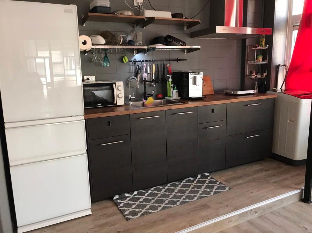 a kitchen with black cabinets and a white refrigerator at Fun Kaohsiung Backpacker Hostel in Kaohsiung