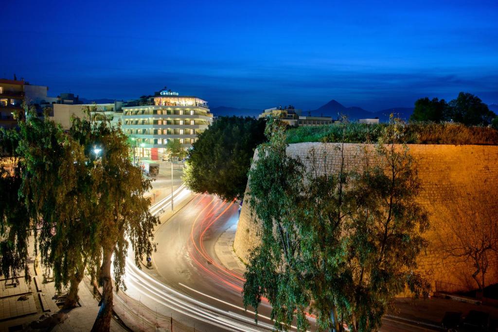 une rue de la ville avec des bâtiments et des arbres la nuit dans l'établissement Castello City Hotel, à Héraklion