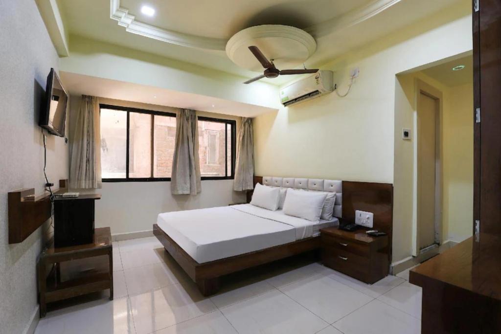 1 dormitorio con 1 cama y TV en NEW JANKI GUEST HOUSE, en Jamnagar