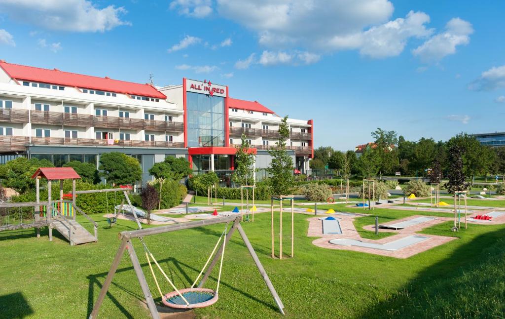 einen Spielplatz in einem Park vor einem Gebäude in der Unterkunft All in Red Thermenhotel in Lutzmannsburg