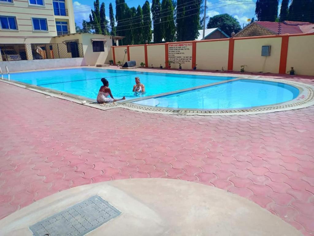two children playing in a swimming pool at Roma Stays Sunset Holiday Apartments 3Bedrooms & swimming pool in Mombasa