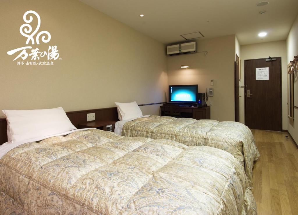 Hakataにある博多　由布院・武雄温泉　万葉の湯のベッド2台とテレビが備わるホテルルームです。