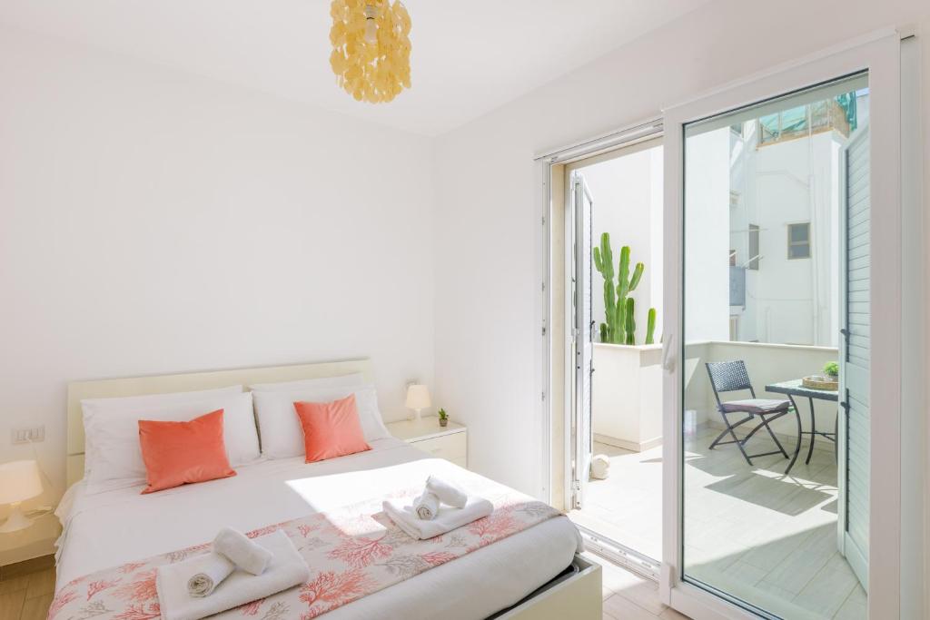 ein weißes Schlafzimmer mit einem Bett und einem Balkon in der Unterkunft DELFINO - Ampio Appartamento a 40 metri dalla Spiaggia in Lido Conchiglia