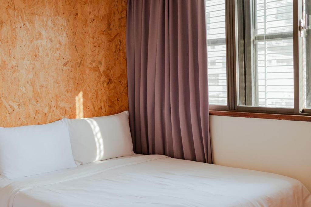 a bed in a room with a window and a white bedvisor at Light Hostel - Tainan in Tainan