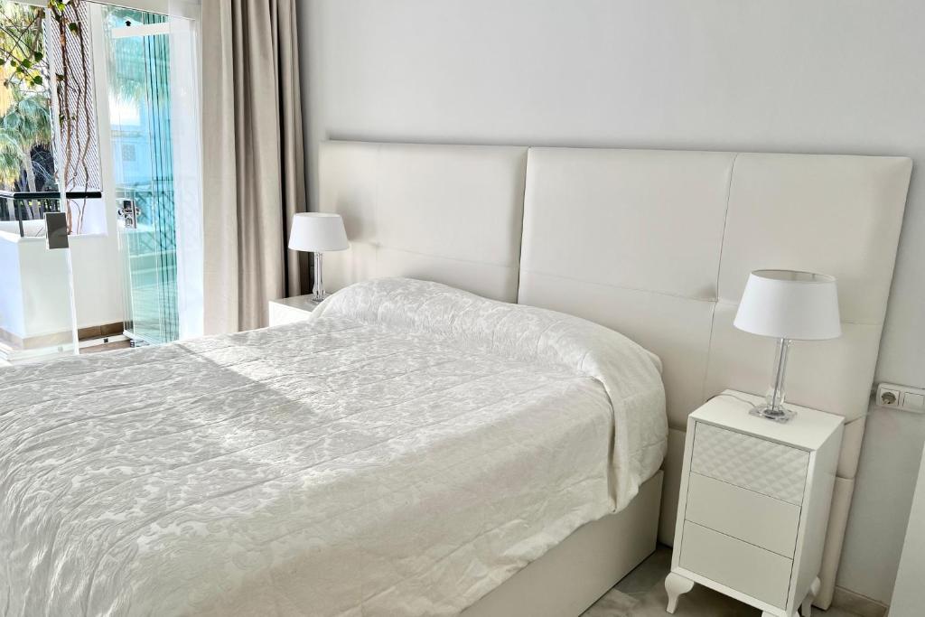 een witte slaapkamer met een bed en een raam bij MI CAPRICHO BEACHFRONT- P301 Apartment with sea view in Mijas Costa
