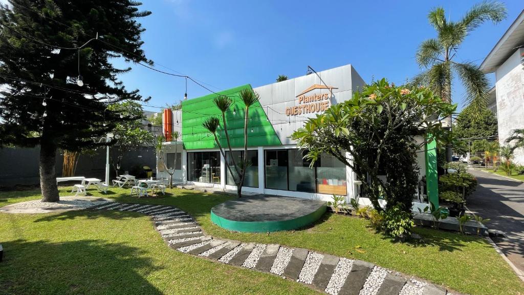 ジョグジャカルタにあるPlanters Guest Houseの緑白の木々と草の建物