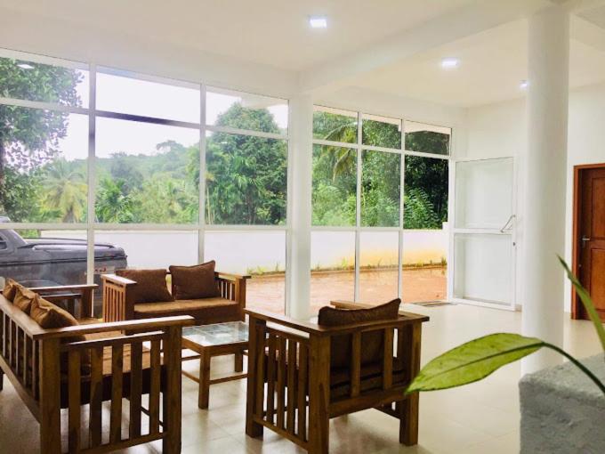 uma sala de estar com cadeiras, um sofá e janelas em Panorama Holiday inn-Pelmadulla em Ratnapura